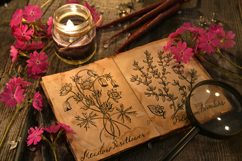 A book surrounded by candles and flowers. Read to learn how to perform a love spell.