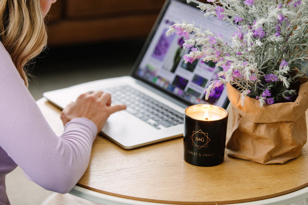 a scented candle burning in the office space, next to a woman working on a computer