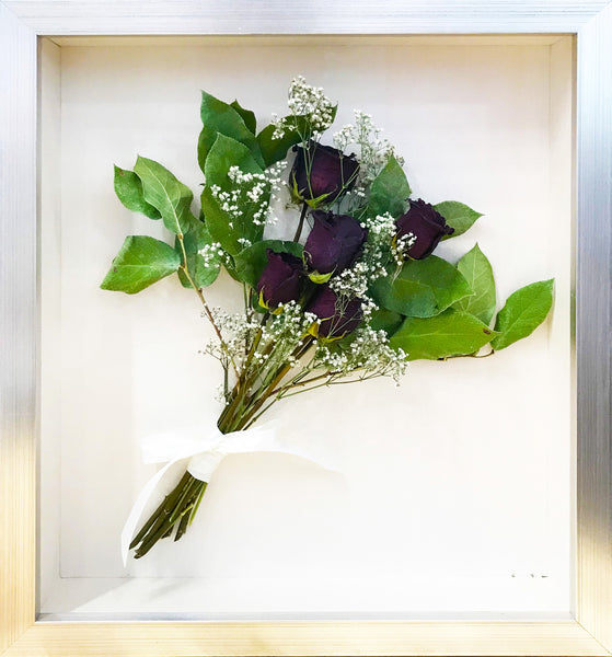 Dried bouquet of red roses displayed in a silver shadowbox.