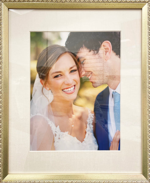 Close up photograph of bride and groom with bride smiling towards the camera custom framed in gold frame.
