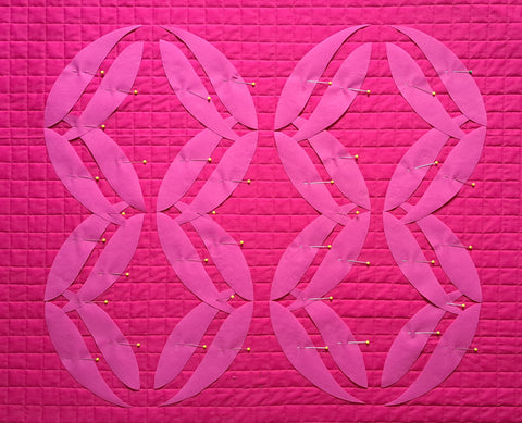 photo of all appliqué templates for PinkBomb 88 wall quilt placed on the  cross hatched fabric.