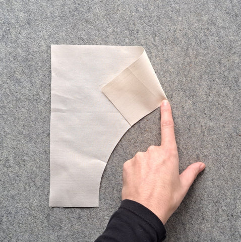 An arch piece with one of the edge folded to meet the centre crease and finger pressed.