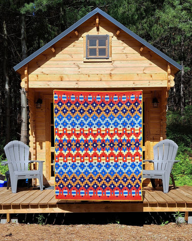 Photo of Alentejana Quilt pattern by ships and violins in front of a cabin. 