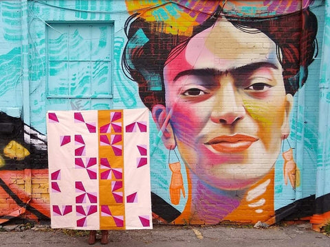 butterfly waltz finished quilt in front of street art depicting Frida Kahlo