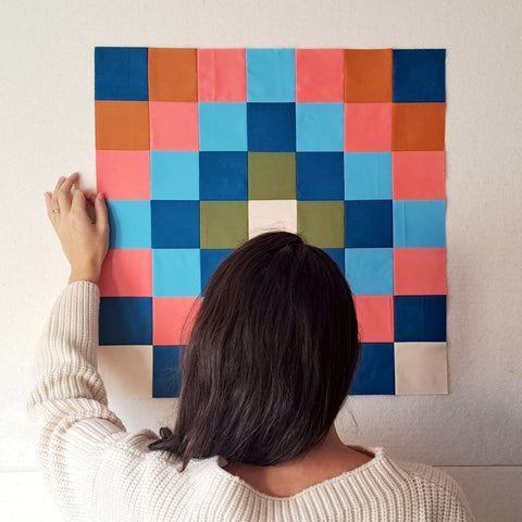 Cristina De Miranda, designer of Ships and Violins, faces a patchwork block on her design wall.