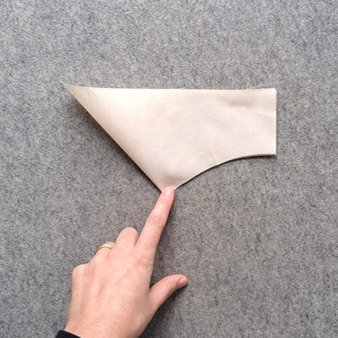 An arch piece folded in half with a finger pressing the centre crease.