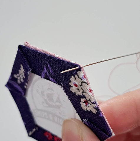 Photo of a needle puncturing the hexagons for english paper piecing