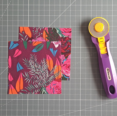 image of two 5 inch fabric squares on a cutting mat with a rotary cutter