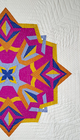 A baby quilt version of the Nesting Phoenix in pink, yellow, cornflower and navy on a cream background.