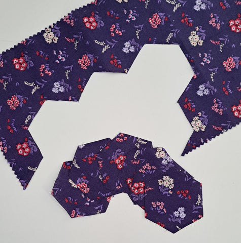 Photos of hexagons cut from purple floral fabric and the fabric remnants