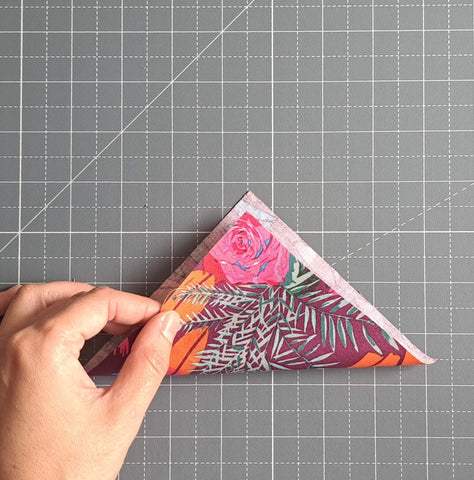 image of hand folding a 5 inch fabric square in half diagonally