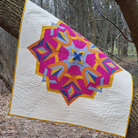 finished nesting pheonix quilt hanging over a tree branch