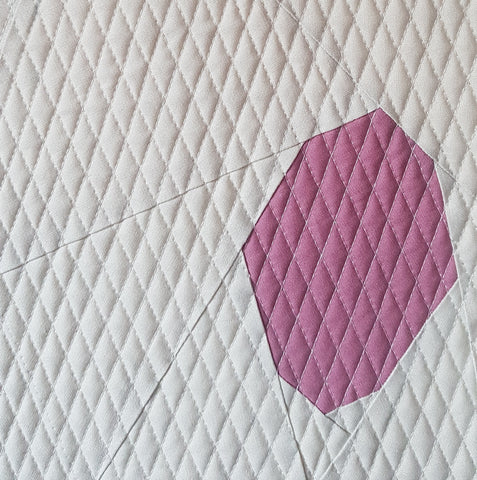 A pink abstract coconut on a white background and quilting with a diamond grid.