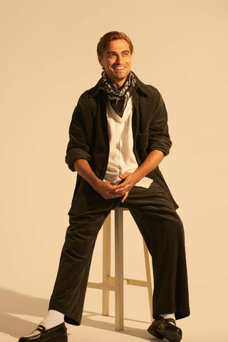 Rhys Martin sitting on stool wearing coral spray scarf