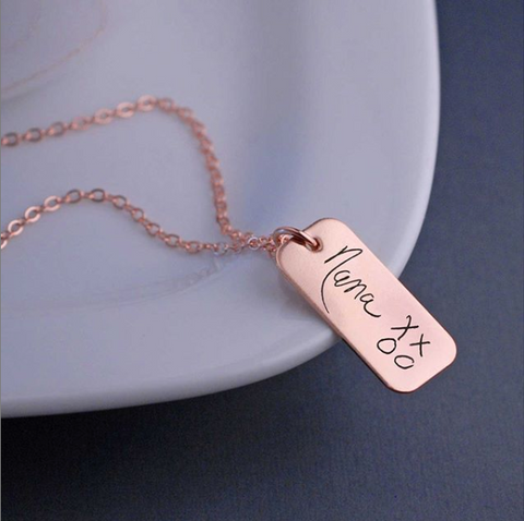 Rose gold necklace with “Nana XXOO” engraved in child’s handwriting on pendant.