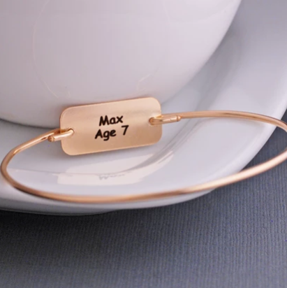 Reverse side of engraved child’s artwork bracelet, showing child’s name and age “Max Age 7”.