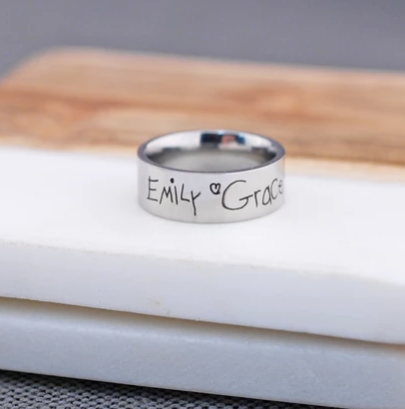 Two children’s signatures engraved on a stainless steel ring.