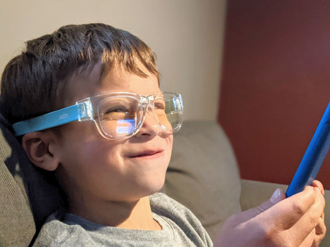 Boy browses iPad while wearing blue blocking snappies glasses