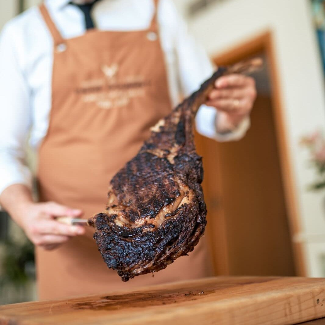 Chef holding up a grilled tomahawk steak