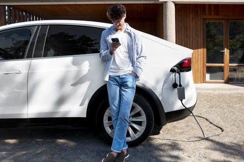 Man leaning against a white electric car while it charges