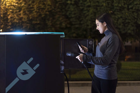 Female using a commercial EV charger at night