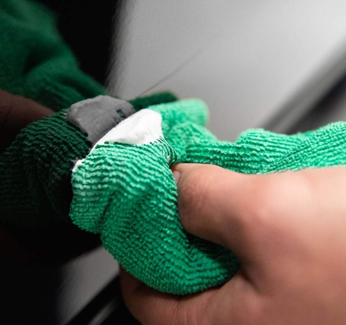 turtle wax scratch repair and renew being applied with a green microfiber cloth on a scratched black car paint