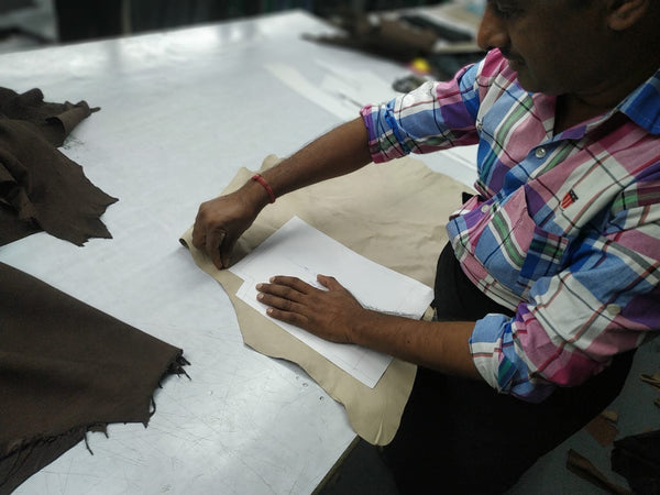 a man in a factory, placing a pattern piece on a piece of upcycled leather