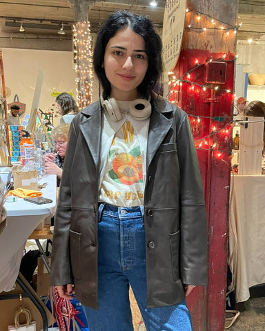 a girl wears a chocolate leather blazer over a vintage graphic tee and jeans