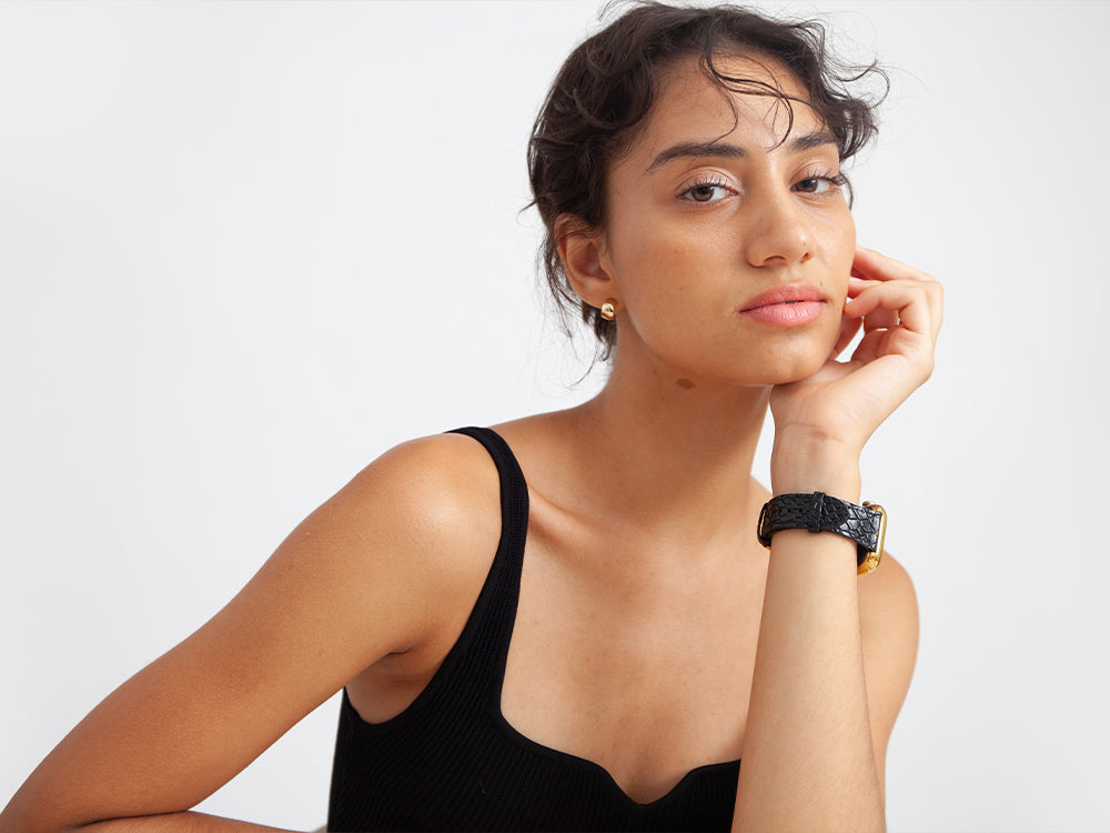 a girl leans her head on her palm, on her forearm is an apple watch with a leather band from HYER GOODS