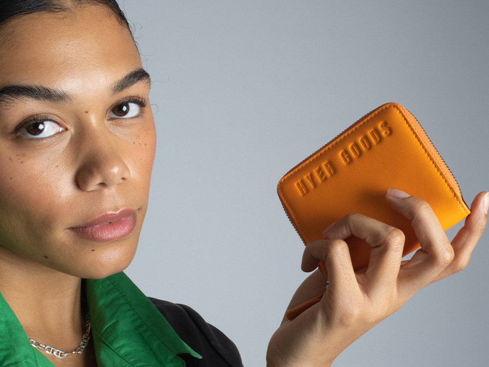 a girl holds a bright neon orange zip wallet