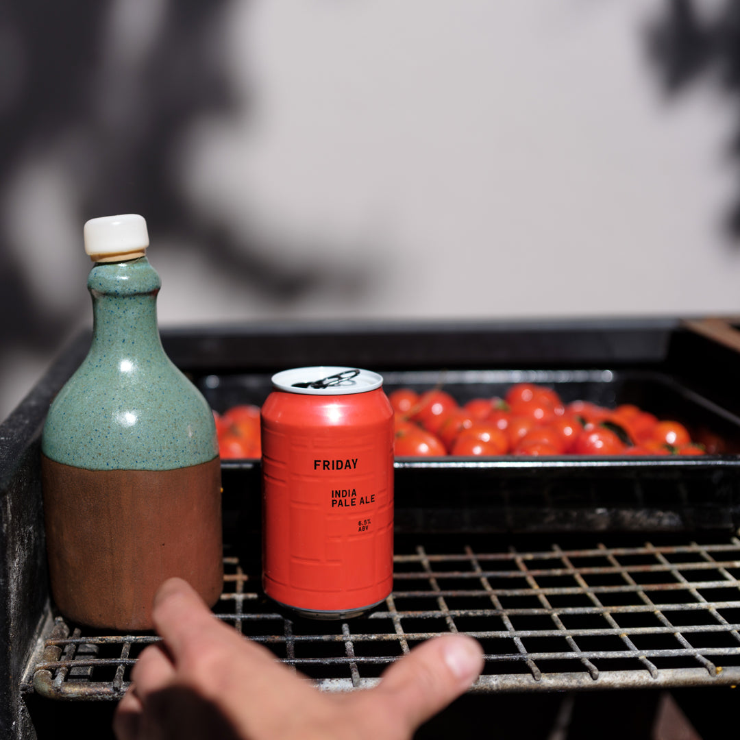Man reaching for AND UNION FRIDAY India Pale Ale craft beer in front of olive oil and tomatoes