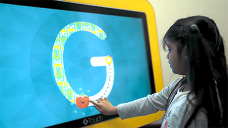 image of a young girl at the yellow Genee Touch Table using the interactive screen