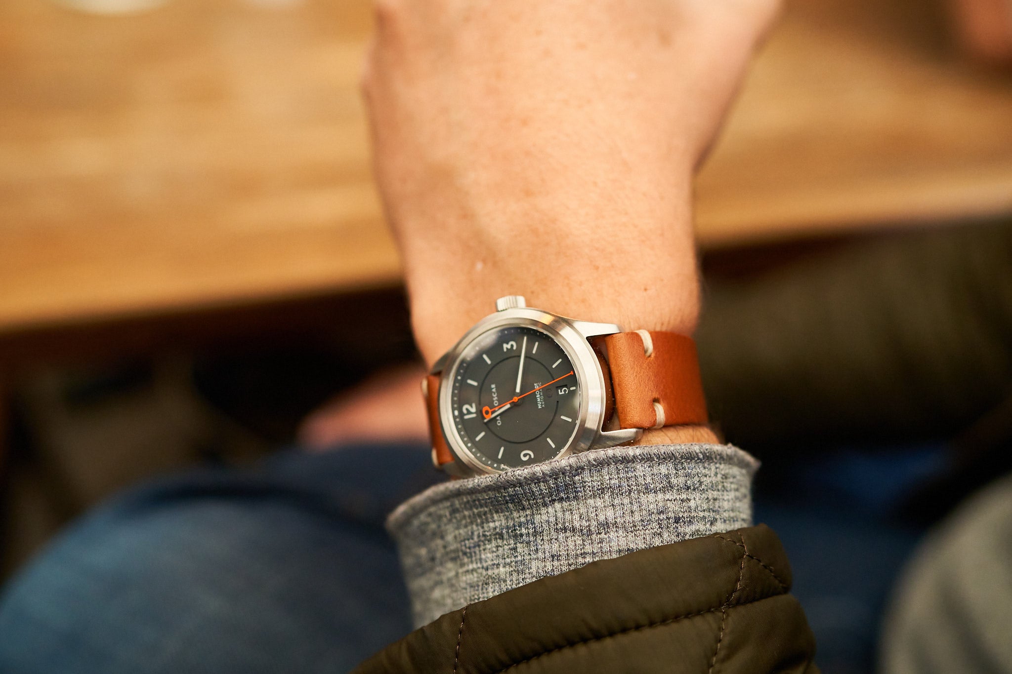 Image of a grey dial Oak & Oscar wrist watch with leather strap on wrist with a grey sweater