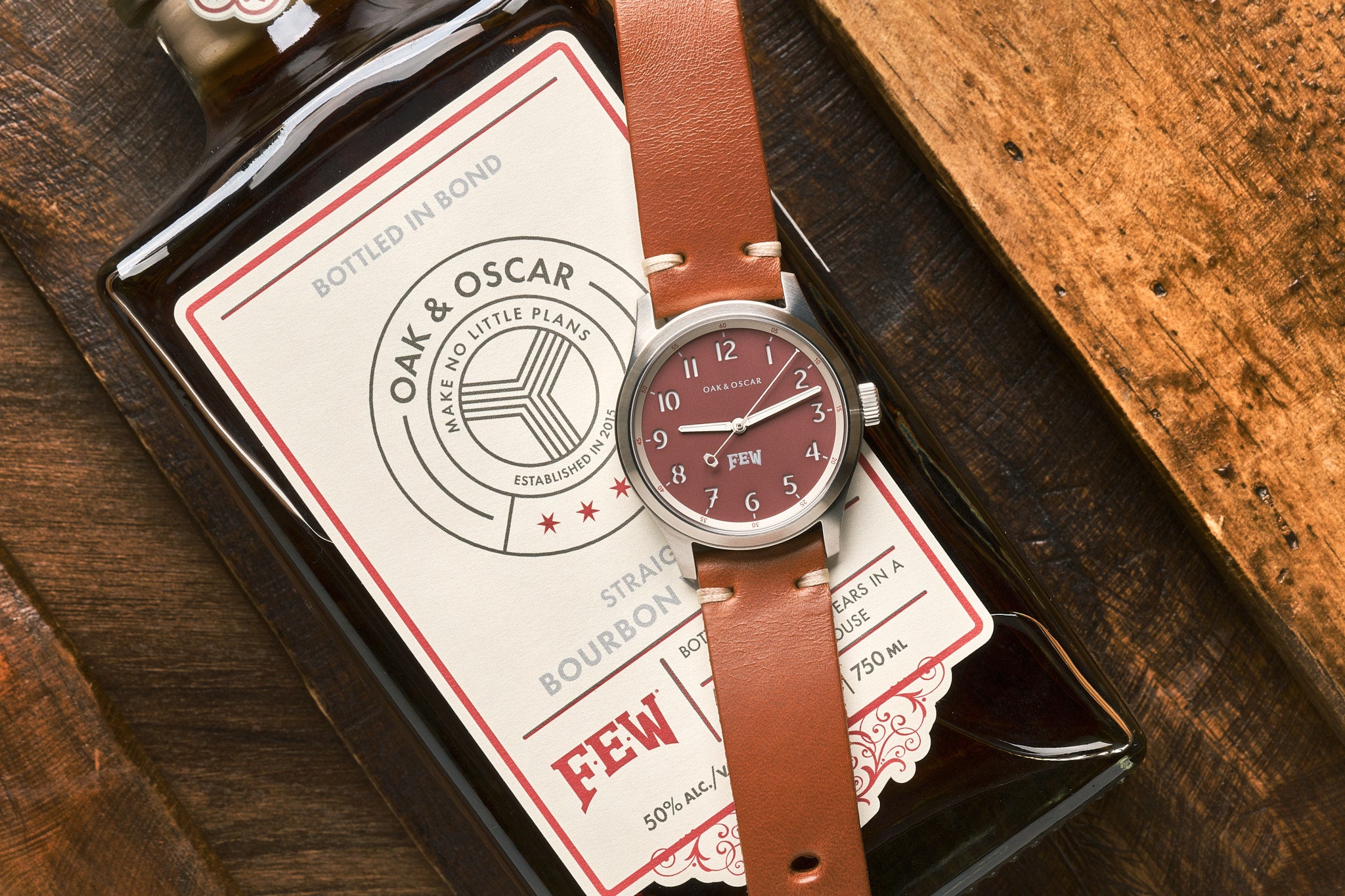 Watch with light red, deep salmon color dial sitting on top of bourbon bottle