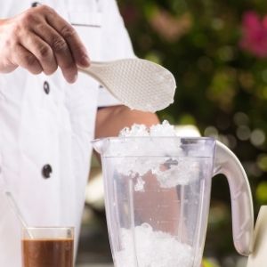 Hand spooning ice into a blender