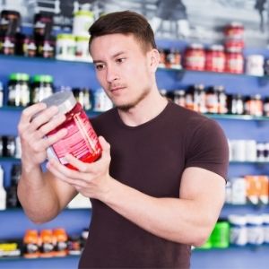 Man looking at nutritional label on a protein powder supplement