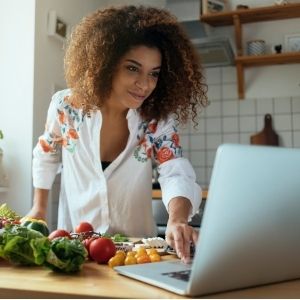 Woman looking at recipes on computer and preparing to make a meal