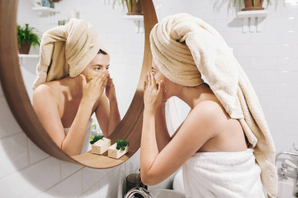 a woman exfoliating her face | The Guilty Woman 