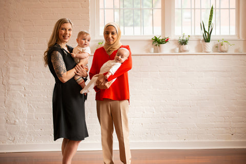 Two moms standing and posing with babies in their arms