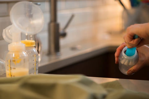 Woman's hands washing breast pump bottles