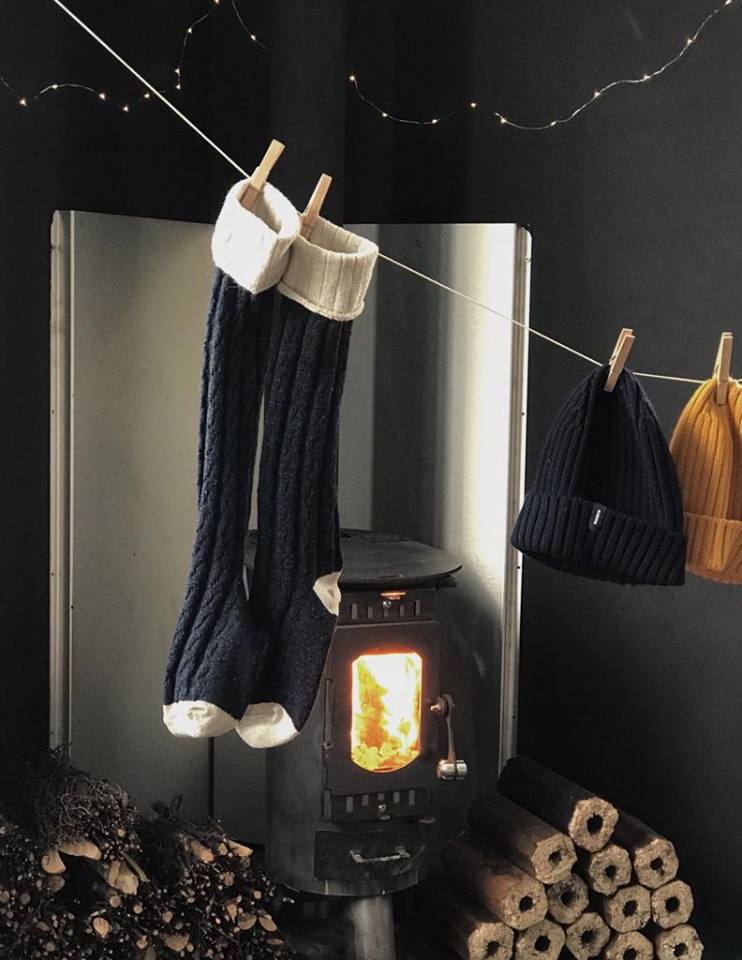 Finisterre accessories hanging infront of an Anevay woodburning stove