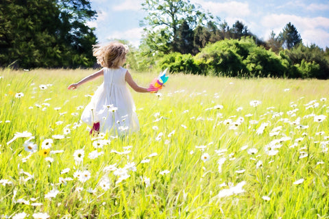 girl running through a field of daisies