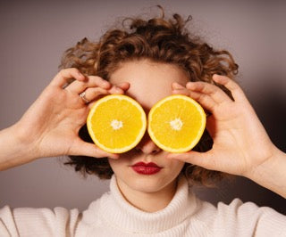 Woman holding citrus fruit to her face