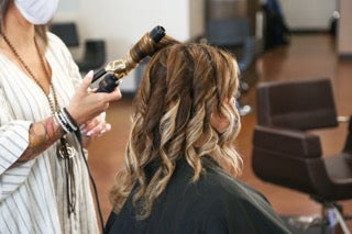 Woman having her hair curled by a stylist