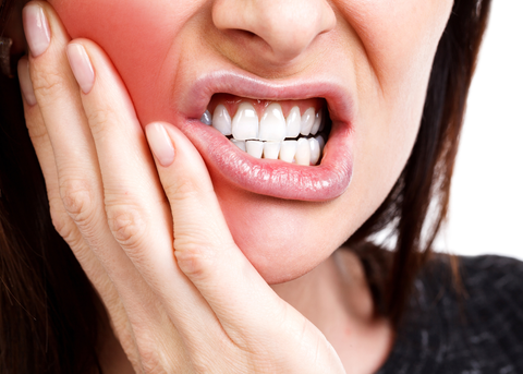 Image of person experiencing a toothache, holding their cheek in discomfort teeth health