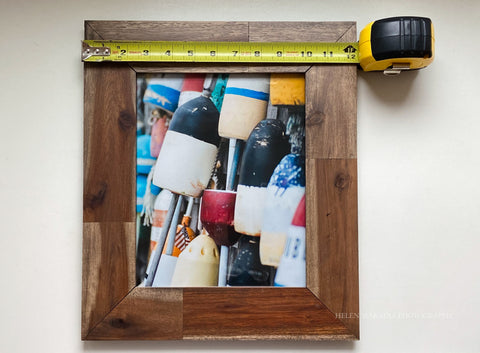 Measuring a framed photograph with a measuring tape for hanging on a wall.  