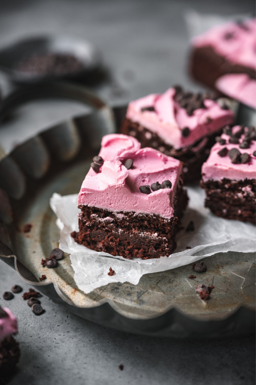 Brownie squares with pink frosting and chocolate chips as garnish.