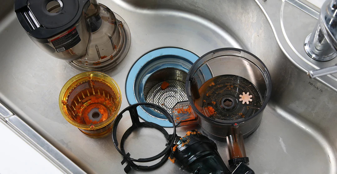 Unwashed juicing parts sitting in an empty sink.