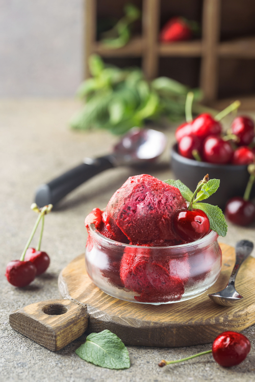 cherry ice cream scoops in a glass bowl with cherry garnish