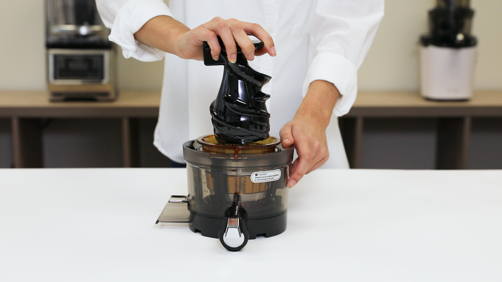 Inserting the Kuvings REVO830 juicing screw into the center of the juicing strainer.